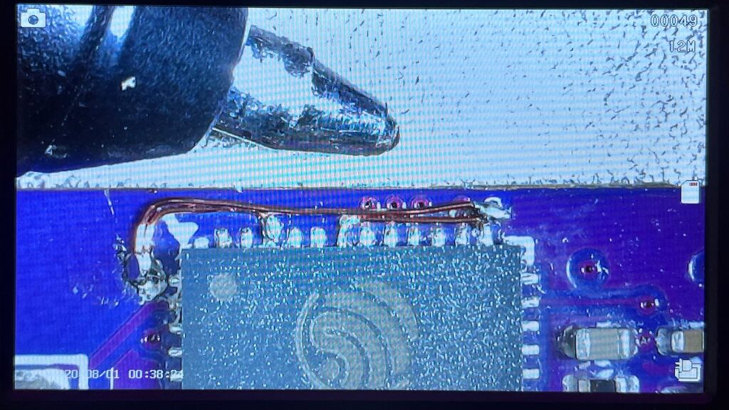 Magnified view of enamelled-wire links repairing missing ESP32 power connections